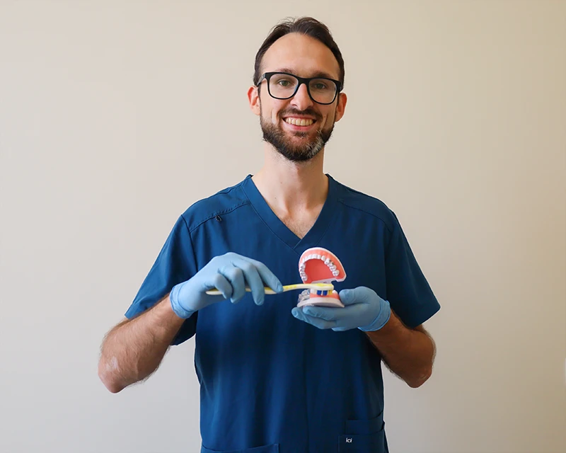 Instruktaż higieny jamy ustnej – lekarz z modelem szczęki i szczoteczką